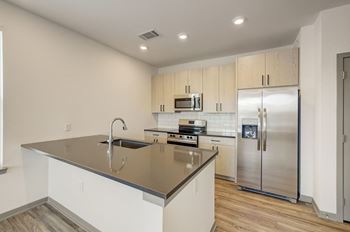A kitchen with a large island and stainless steel refrigerator